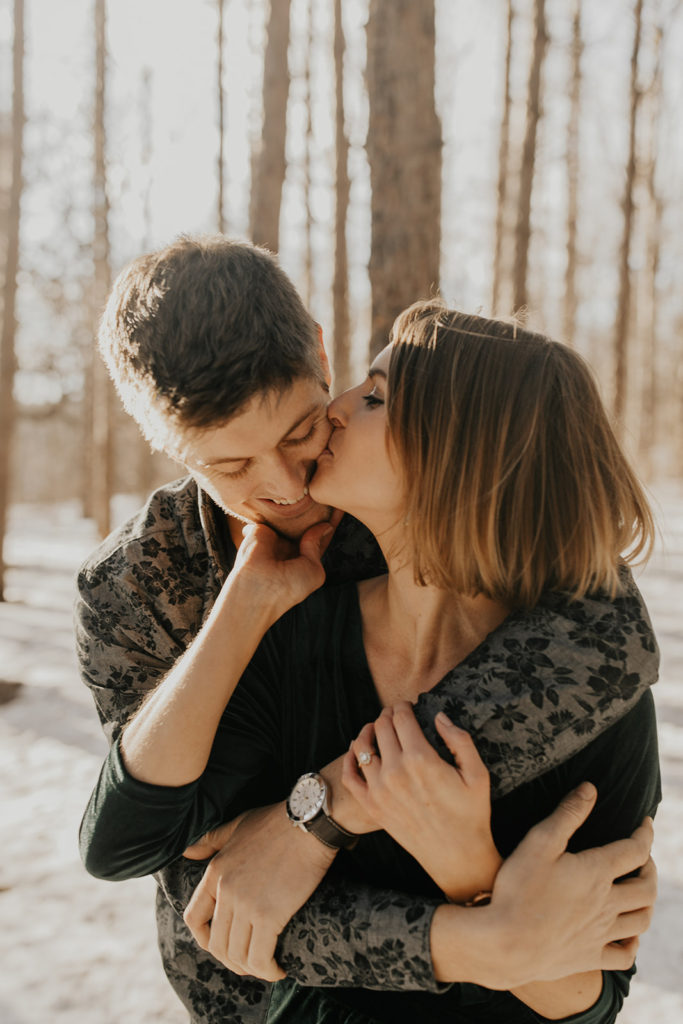 engaged couple kissing in the snow
