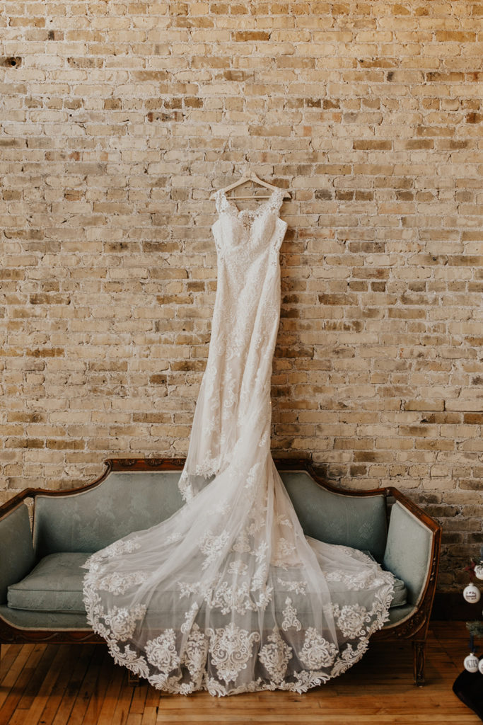 wedding dress hanging up on brick wall 