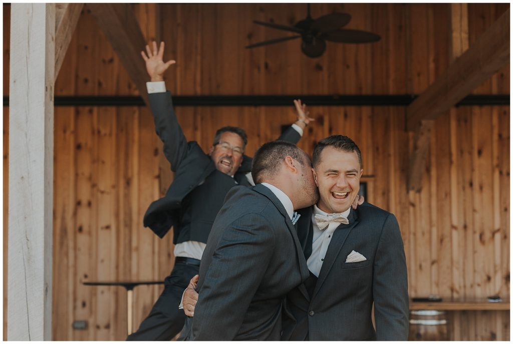 groom and groomsmen taking portraits in front of the barn at the bog