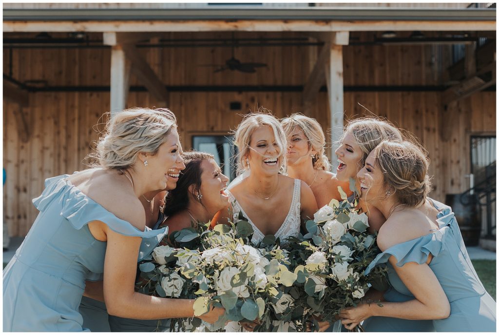 bride and bridesmaids wearing dusty blue dresses holding bouquets with white roses and eucalyptus
