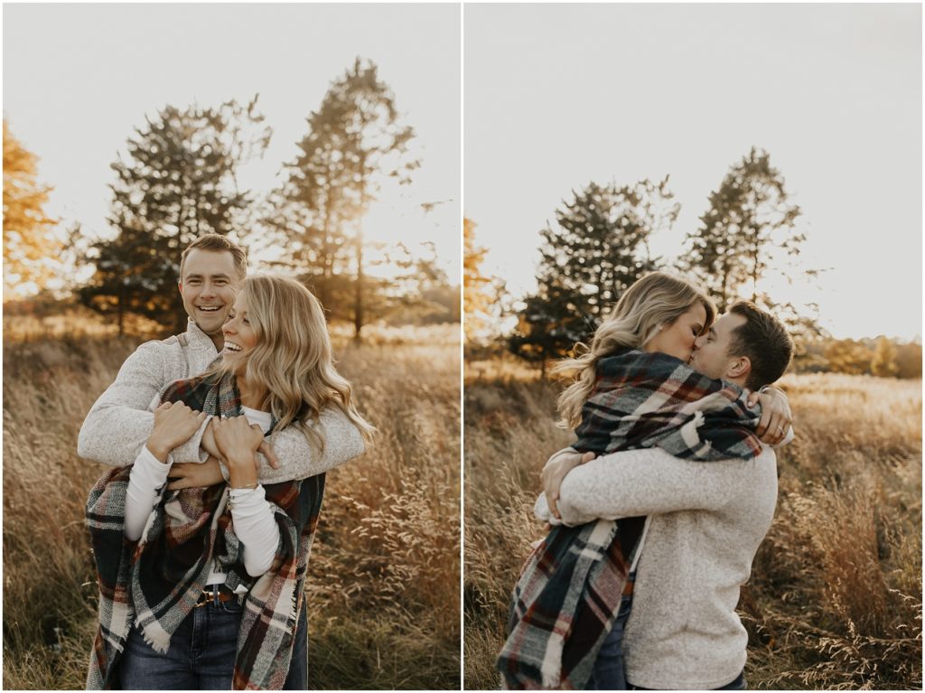 engaged couple holding each other and kissing in a sunny meadow
