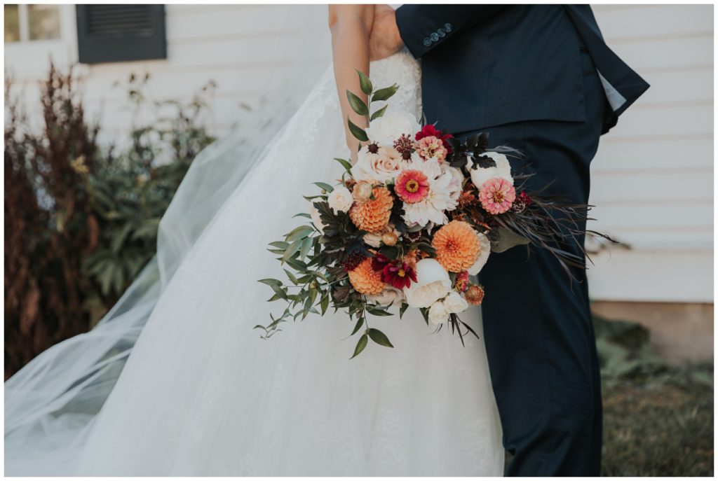 bride and groom portraits on wedding day at lac la belle, bride holding burnt orange and blush bouquet