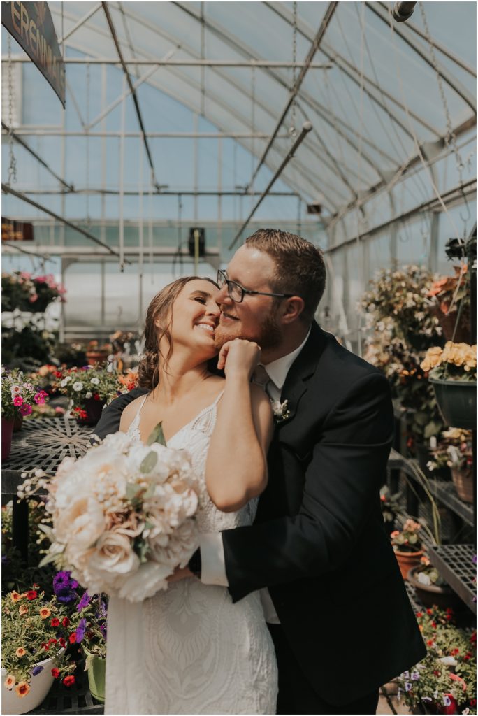 bride and groom posing for portraits in a greenhouse on their wedding day 