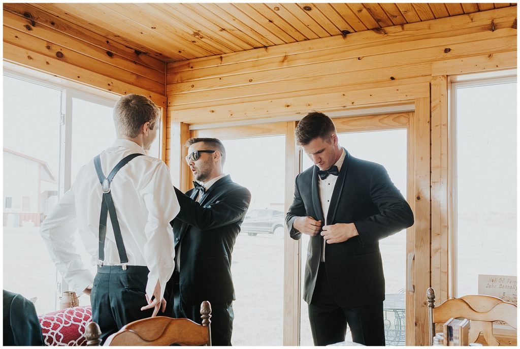 groom and groomsmen getting ready in dressing room on wedding day
