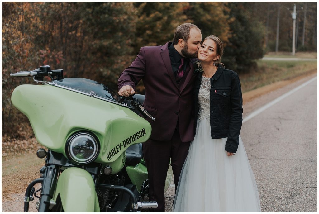 bride and groom posing next to their motorcycle on their wedding day